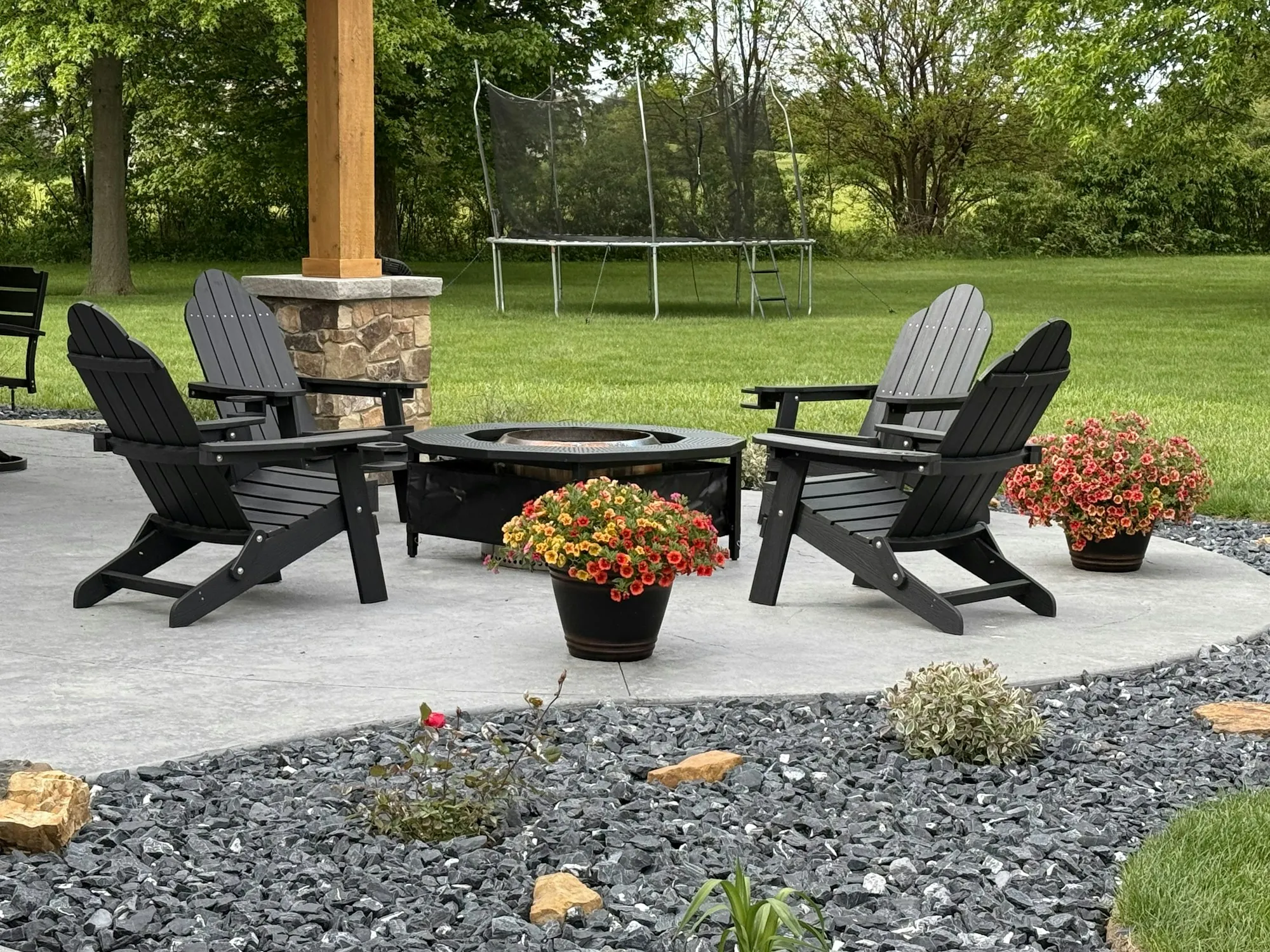 Adirondack chairs around a fire pit on a concrete patio